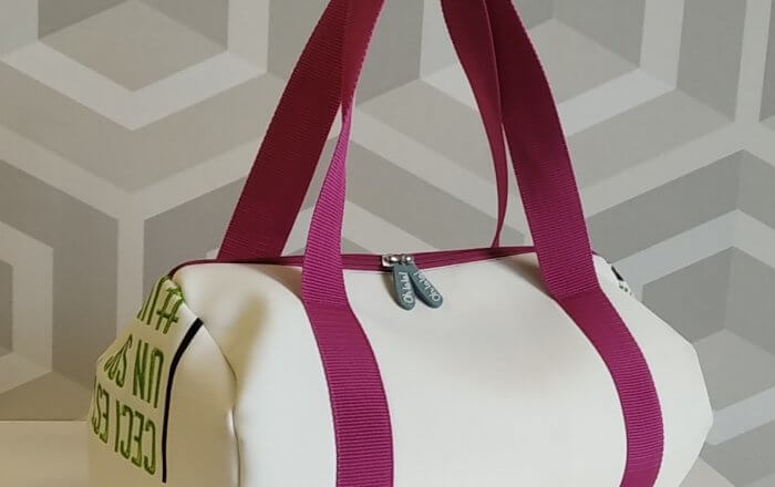 Photo du sac polochon confectionné en matières upcyclées, crème avec anses roses